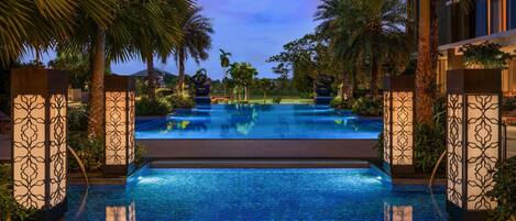 A swimming pool with a tiled floor, surrounded by palm trees and decorative panels.