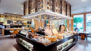 A buffet area with a variety of food options, a coffee station, and a seating area with tables and chairs. - Hilton Bangkok Suvarnabhumi Golf Resort & Spa (Bang Phli)