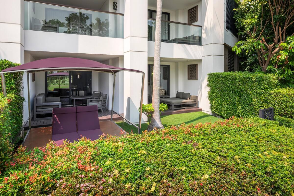 A modern outdoor seating area with a covered patio, a pool, and a well-maintained garden.