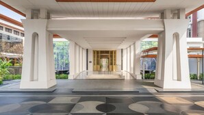 A modern building entrance with a covered walkway, a central door, and a tiled floor. - Hilton Bangkok Suvarnabhumi Golf Resort & Spa (Bang Phli)