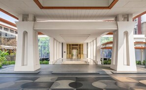 A modern building entrance with a covered walkway, a central door, and a tiled floor.