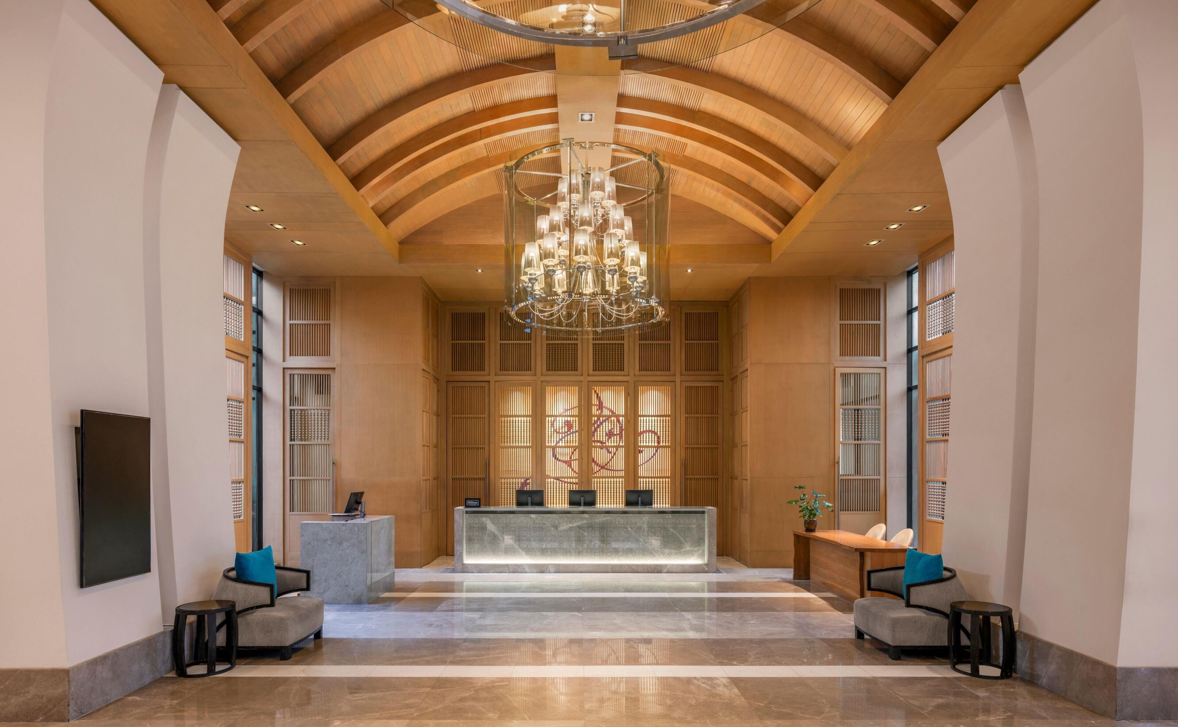 A lobby with a reception desk, seating area, and a chandelier.