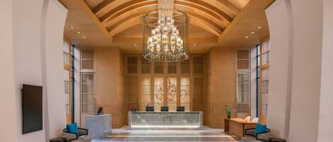 A lobby with a reception desk, seating area, and a chandelier.