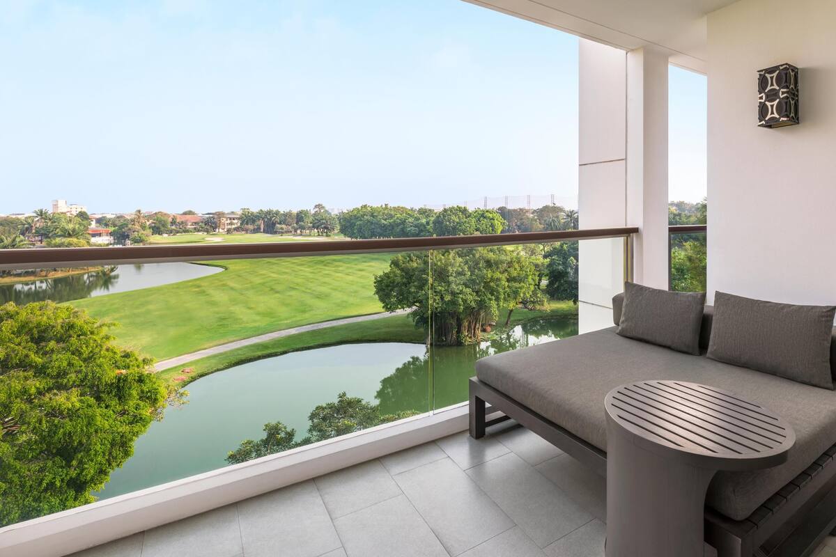 A balcony with a view of a lake, a sofa, and a small table.