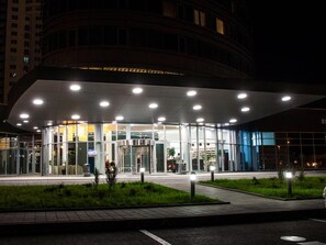 Ein modernes Gebäude mit Glastür, überdachter Wartezone und angelegtem Garten.