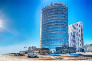 A modern hotel with a curved facade, multiple floors, and a prominent entrance with a glass facade. - Slavyanskaya Hotel (Minsk)