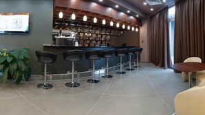 A bar area with a curved counter, multiple stools, a television, and a bar stocked with bottles. - Slavyanskaya Hotel (Minsk)