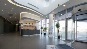 A modern reception area with a curved ceiling, large windows, and a reception desk. - Slavyanskaya Hotel (Minsk)