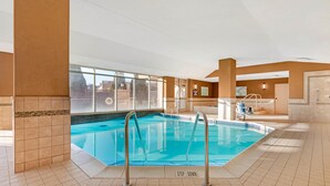 Una piscina interior con paredes de vidrio transparente, suelo de baldosas y un cartel que indica 'Step Down'.