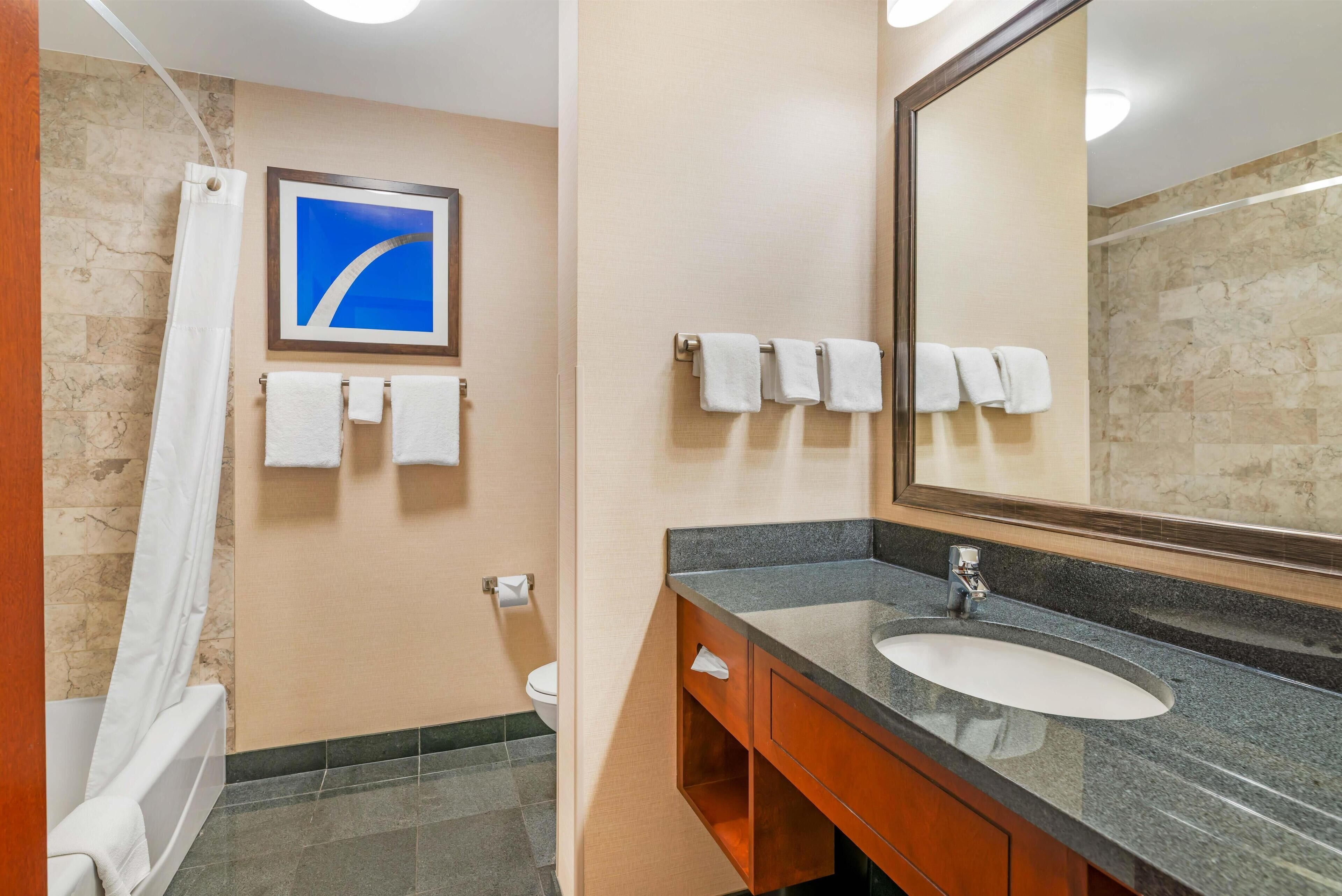 A bathroom with a sink, mirror, and towel rack.
