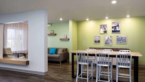 Un comedor moderno con una mesa de madera y sillas metálicas, un sofá con un cojín azul y un banco de madera.