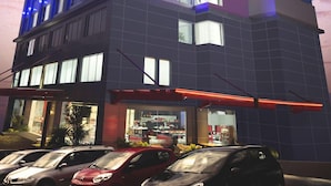 A modern hotel with a prominent sign, multiple floors, and illuminated balconies. - G Suites Hotel by AMITHYA (Surabaya)