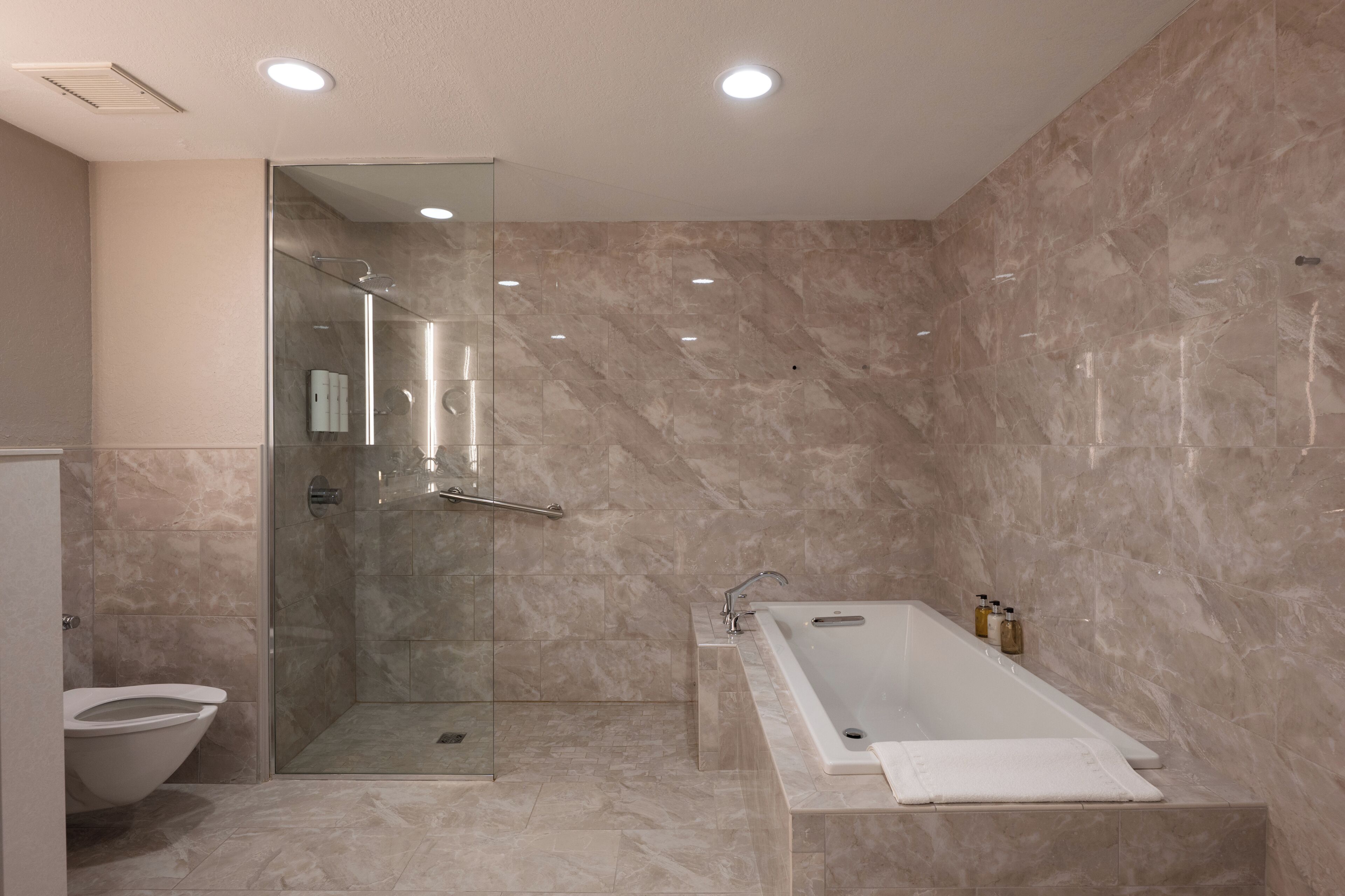 A modern bathroom with a glass-enclosed shower, a freestanding bathtub, and a toilet.