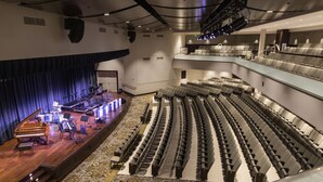 An indoor auditorium with a stage, seating, and a staircase.
