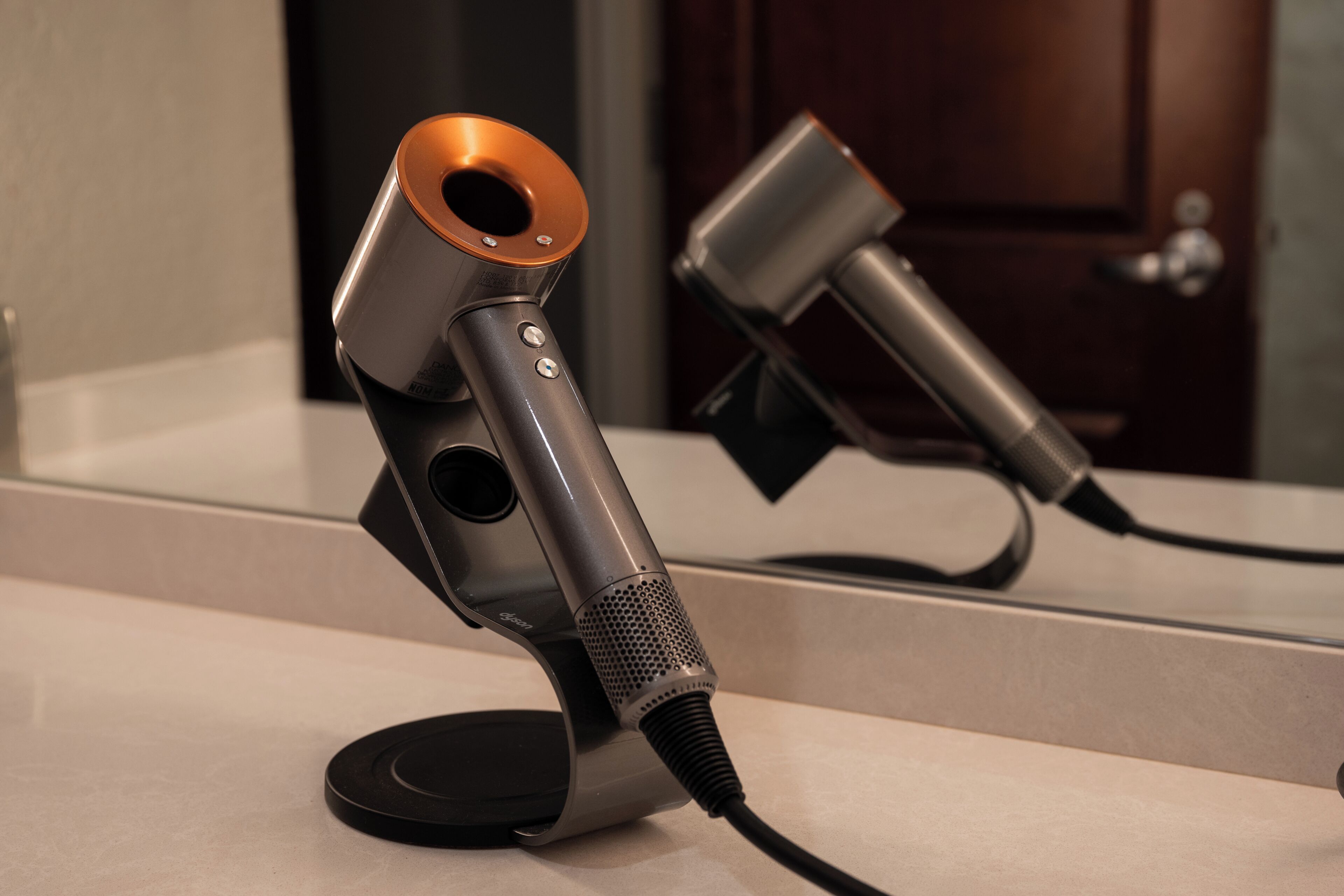 A microphone on a stand with a cord, positioned in front of a mirror.