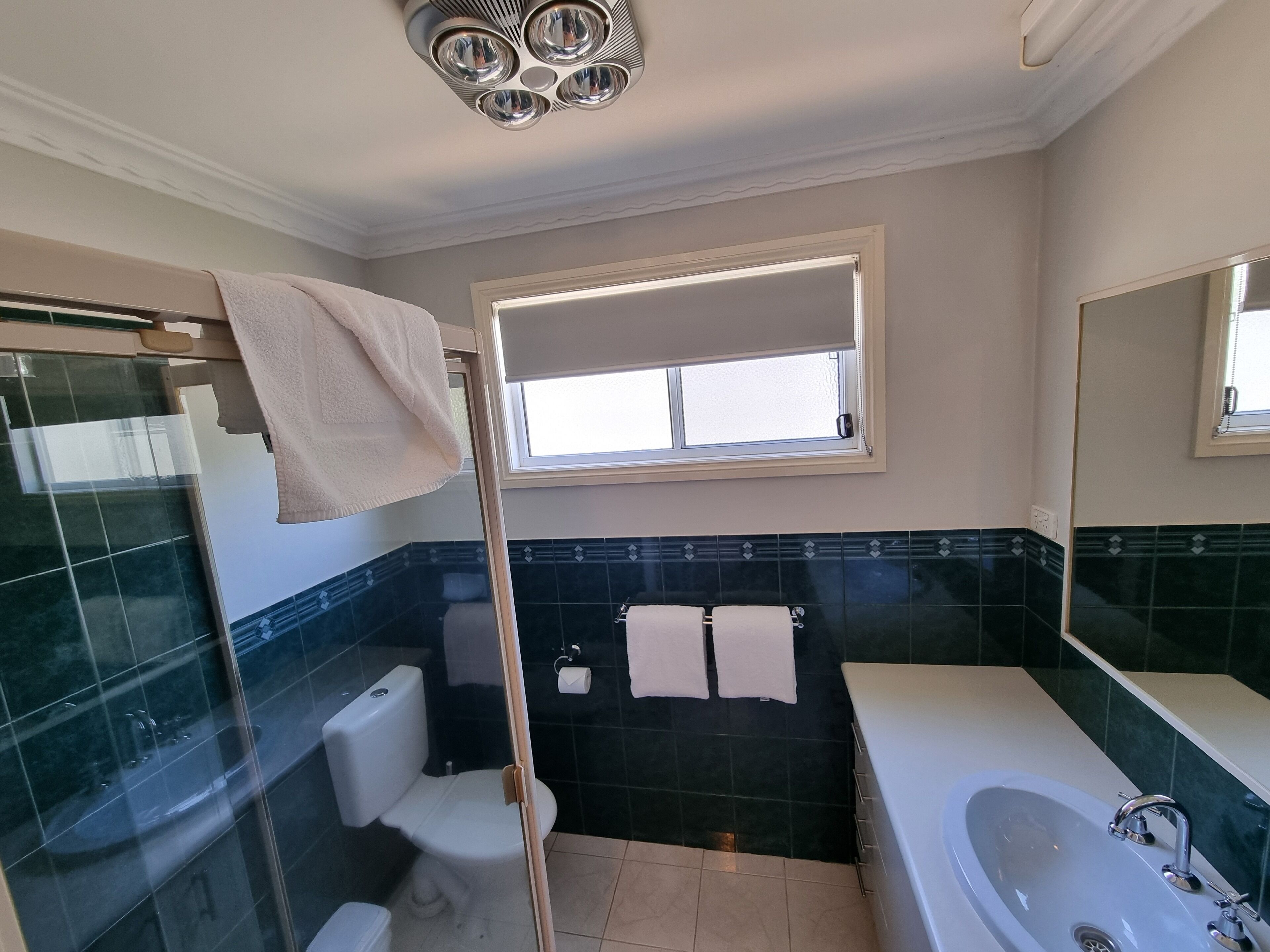 Un baño con mampara de vidrio, inodoro, lavabo y bañera.