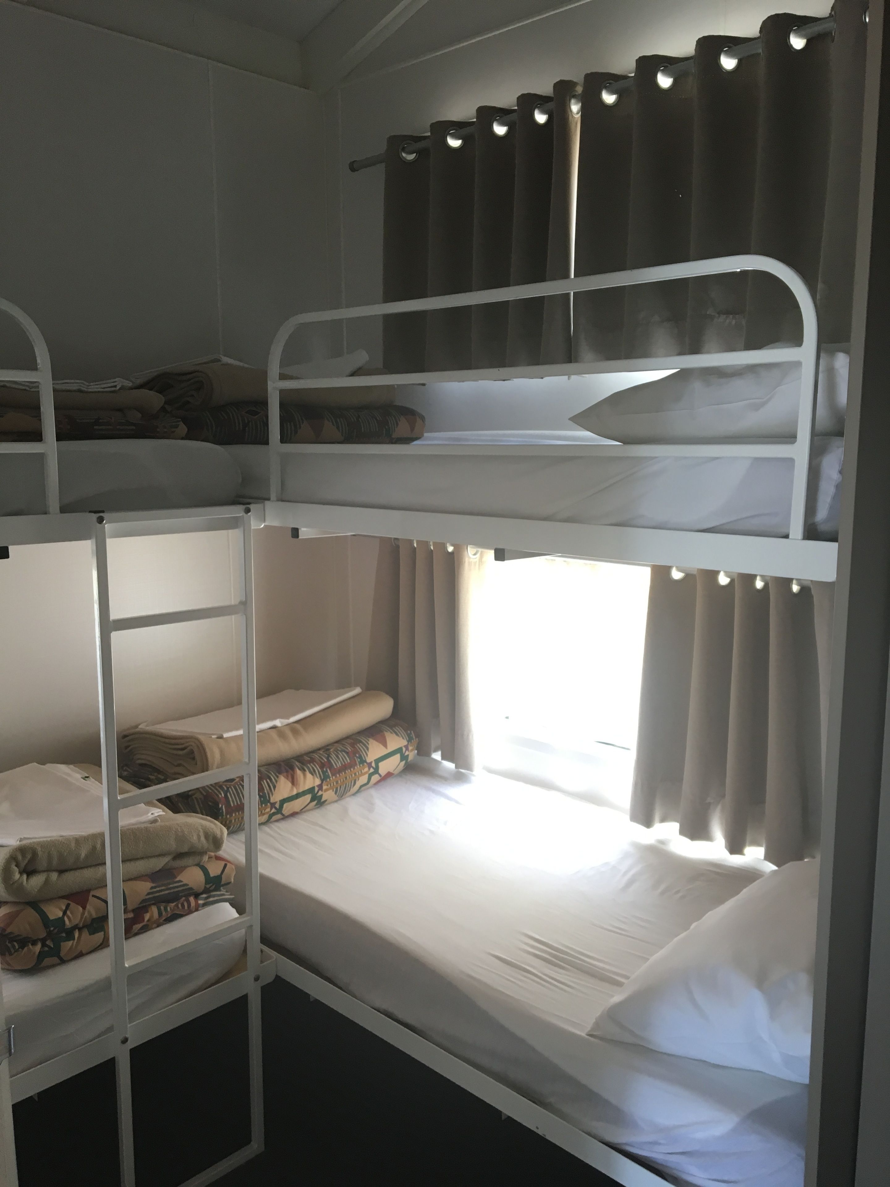 Une chambre avec un lit superposé, une fenêtre et des rideaux.