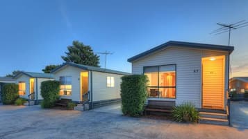 A row of single-story mobile homes with individual entrances, each featuring a small porch and a visible window.