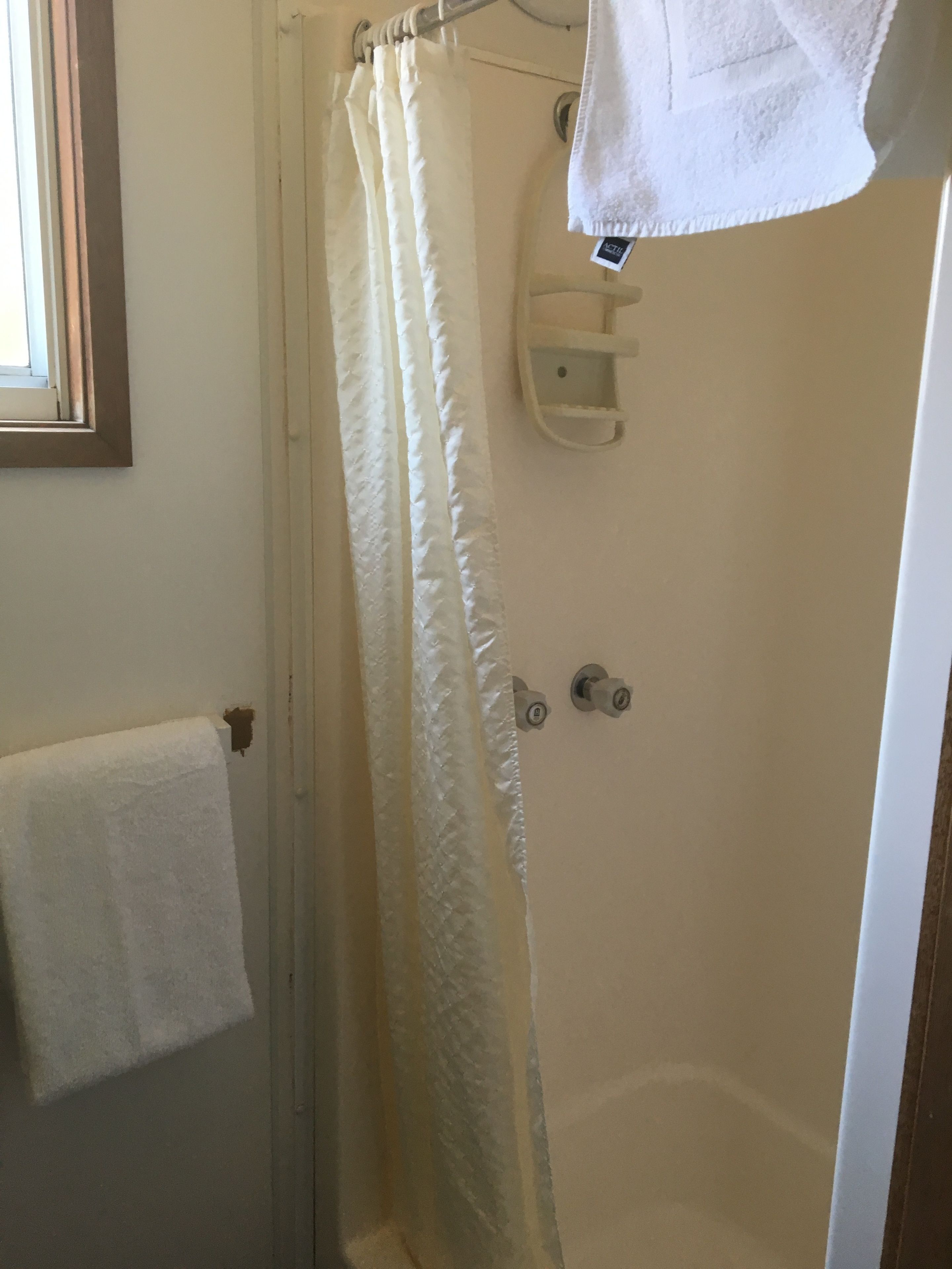 A bathroom with a shower curtain, a towel rack, and a soap dish.