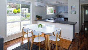 Una cocina moderna con armarios blancos, una isla central con asientos y un amplio ventanal con vistas al exterior.