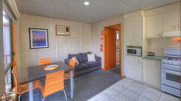A compact living space with a dining table, sofa, and kitchenette.