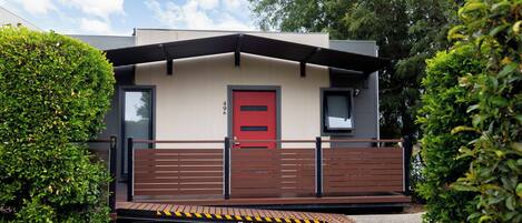 Un edificio moderno con puerta roja, rampa accesible y entrada protegida por un portón.