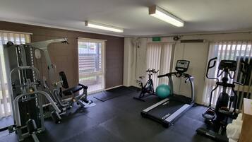 A gym with exercise equipment, a treadmill, and a ball.