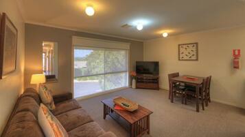 A living room with a sofa, TV, dining table, and chairs.