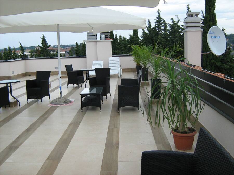A rooftop terrace with outdoor seating, including tables and chairs, and a potted plant.