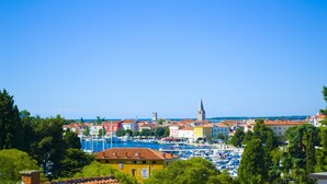 A coastal town with colorful buildings, a prominent church tower, and a marina filled with boats. - Hotel Villa Karda (Porec)