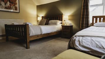 Een slaapkamer met een houten bed, twee nachtkastjes met lampen, een radiator en een raam met gordijnen.