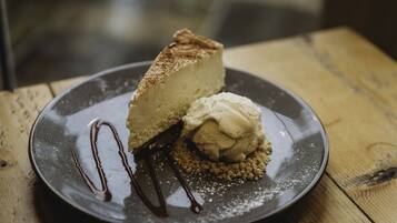 A dessert plate with a slice of cheesecake and a scoop of ice cream on a wooden table.