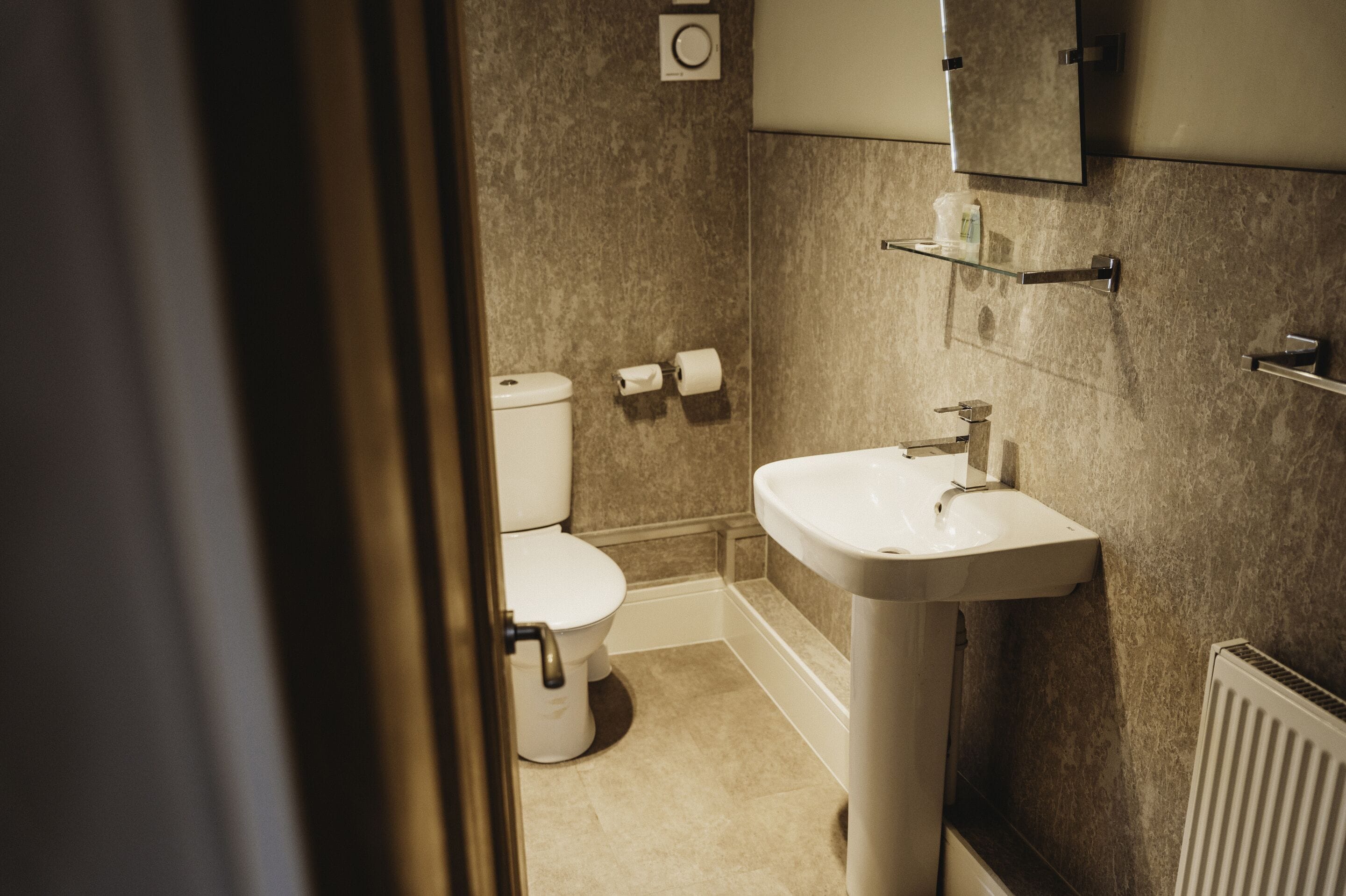 A bathroom with a toilet, sink, and a mirror above the sink.
