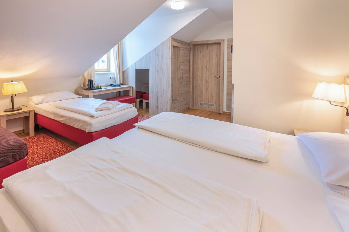 Una camera d'albergo con due letti, una scrivania e un armadio.