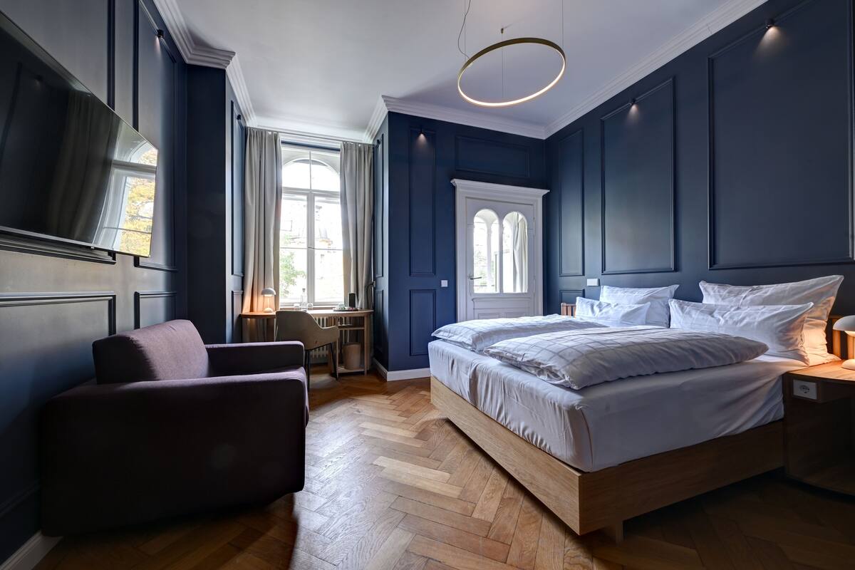 A modern bedroom with a large bed, a desk, and a chair.