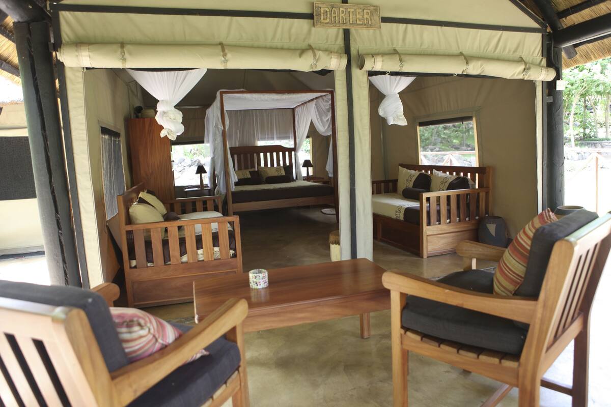 A tented accommodation with a bed, a sofa, and a dining table.