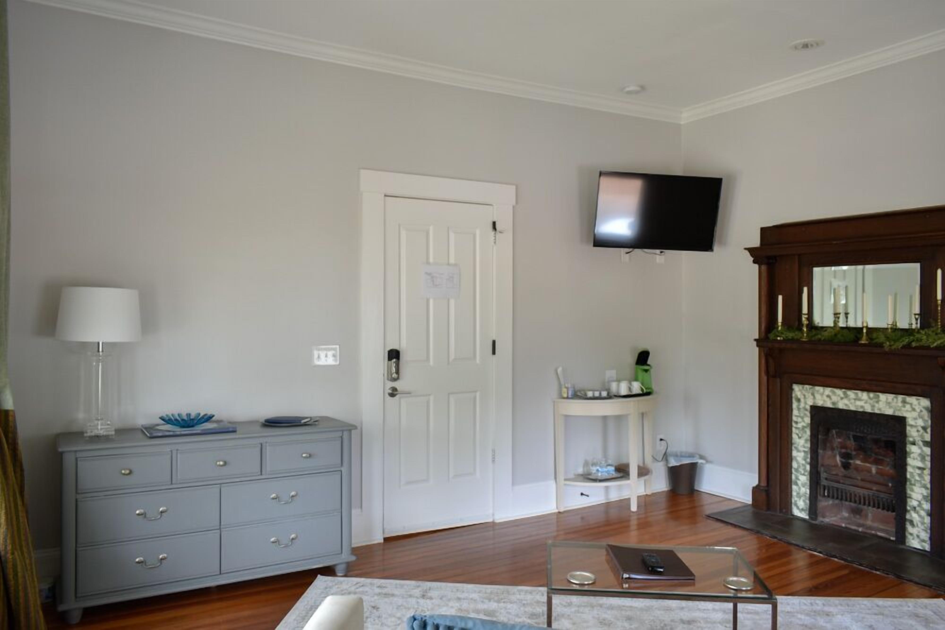 Un salon avec une cheminée, un téléviseur fixé au mur et une commode grise dotée de tiroirs.