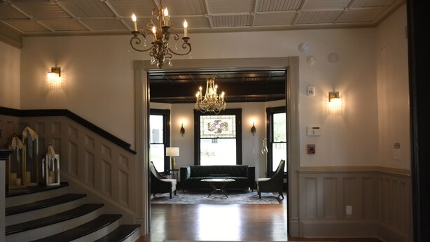 A grand entrance with a staircase, a chandelier, and a sofa in the background. - Sparrow Grove Manor (Monroe)