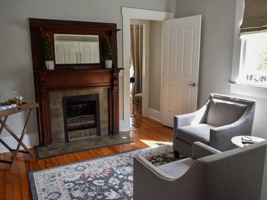 A living room with a fireplace, a gray armchair, a small table, and a patterned rug.