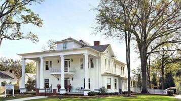 A two-story white house with a front porch, columns, and a small balcony.