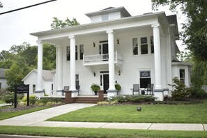 A two-story white building with a porch, columns, and a sign that reads "Sparrow Grove."