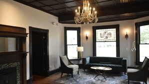 A living room with a chandelier, a fireplace, a sofa, and a coffee table. - Sparrow Grove Manor (Monroe)