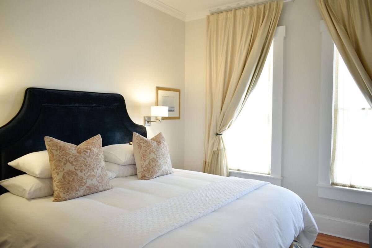 A neatly made bed with a dark headboard, two patterned pillows, and a white bedspread.