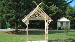 Una estructura d'arbor de fusta en una zona verda amb dues plantes en testos.