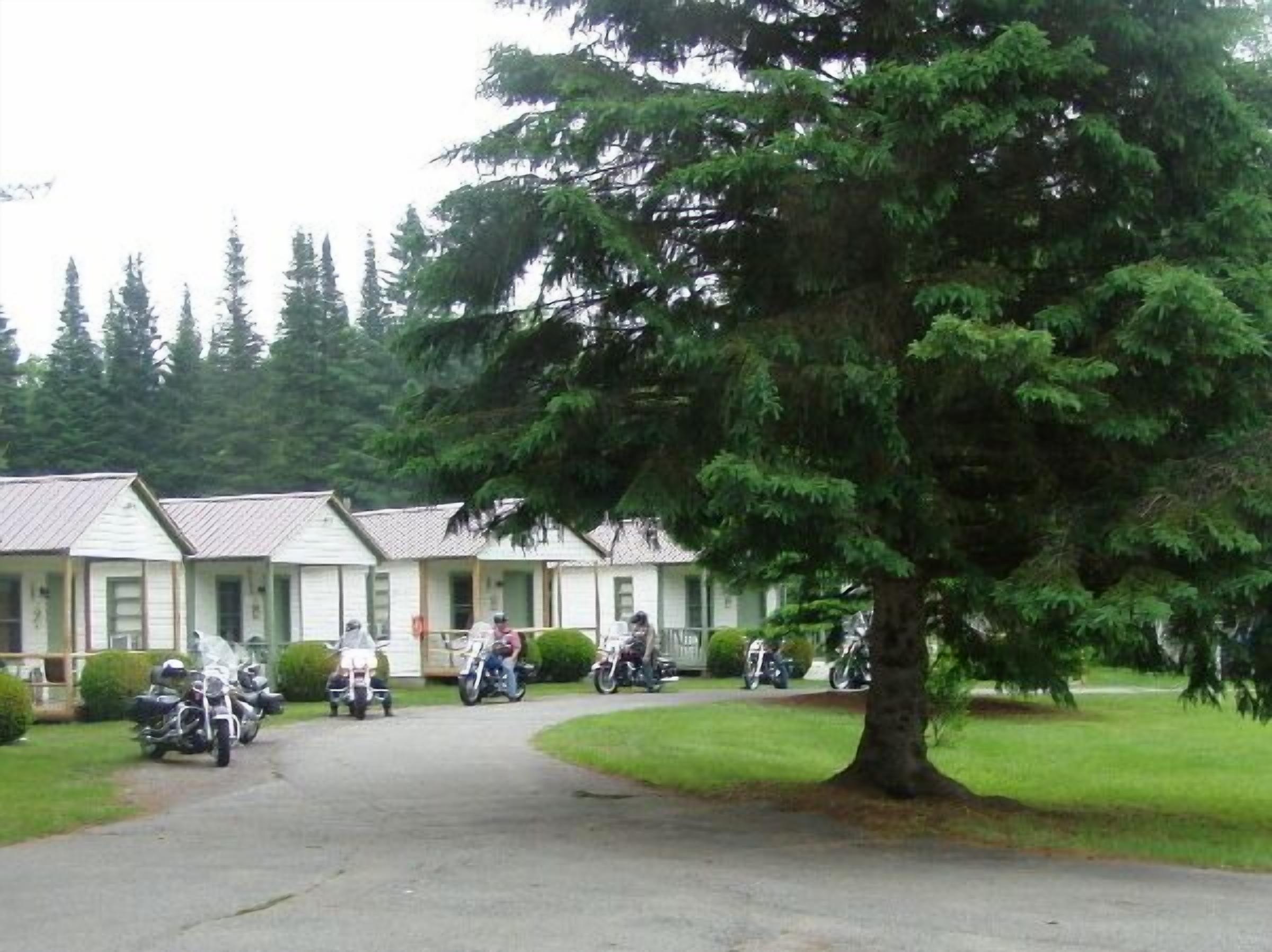 A row of single-story buildings with a paved driveway leading to a parking area.