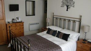 A bedroom with a bed, dresser, nightstand, and a wall-mounted TV. - Adcote House (Llandudno)