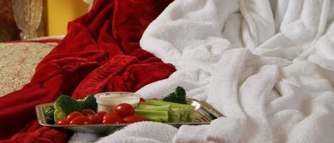 A bed with a red blanket and a white bathrobe.