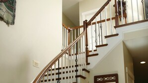 A wooden staircase with a white railing, a mirror, and potted plants. - Seven Oaks Bed & Breakfast (High Point)