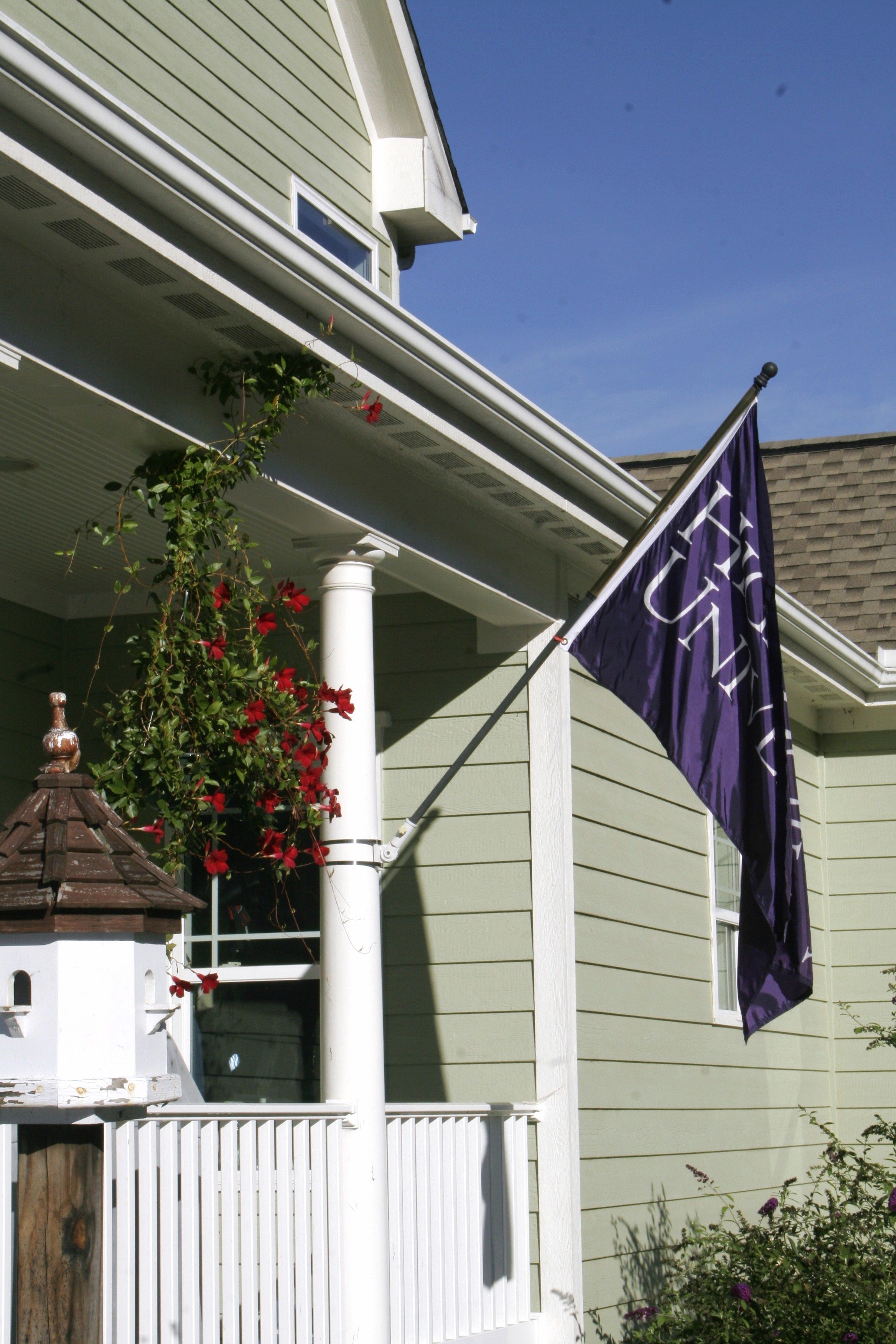 A house with a porch, a small birdhouse, and a flag.