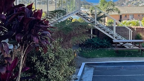 A building with a brick facade, a balcony with a metal railing, and a staircase leading to a parking area. - Ocean View Motor Inn (Merimbula)